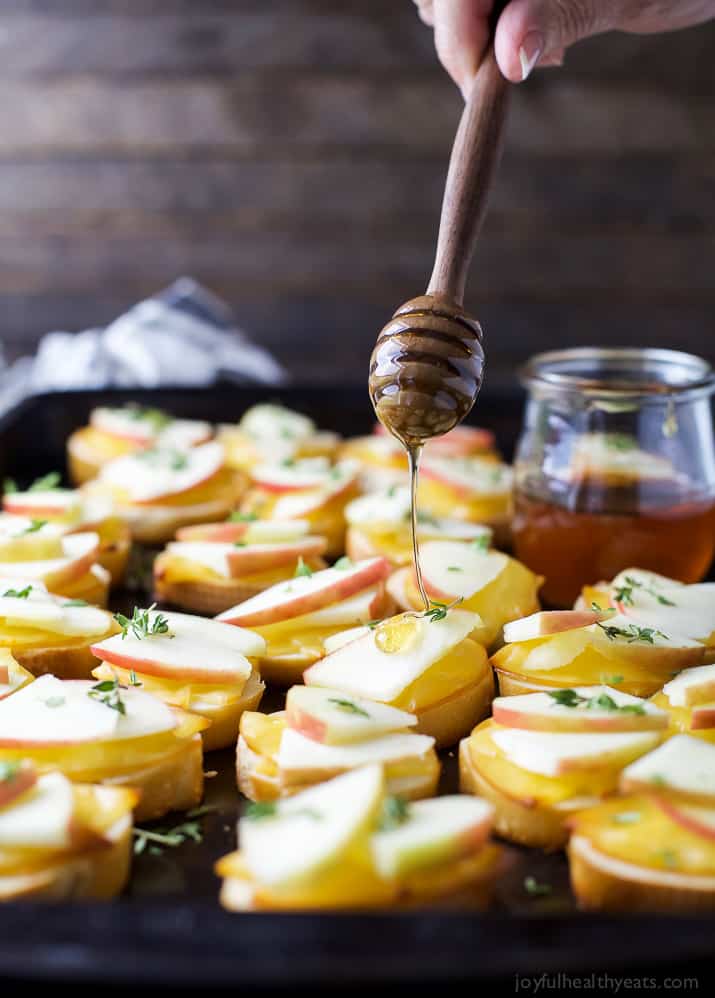 A Pan of Smoked Gouda and Apple Crostini Being Drizzled with Honey