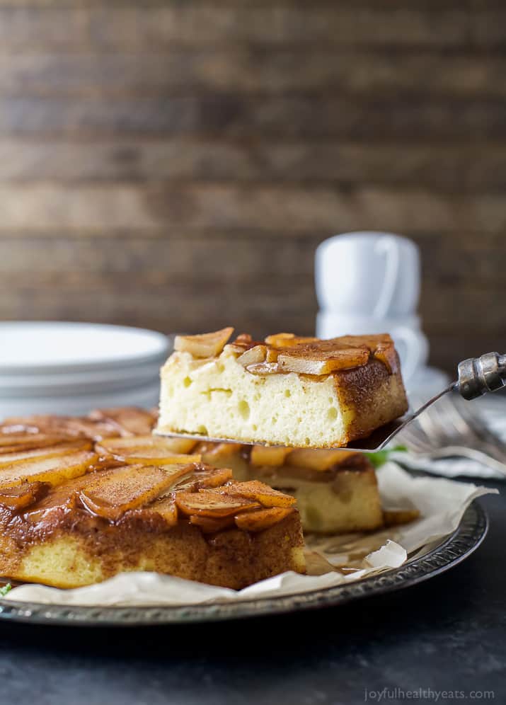 This tender pear upside-down cake recipe with homemade spiced caramel is a fancy-yet-easy dessert for the holidays. Grabbing a slice of pear cake with caramelized pear on top.