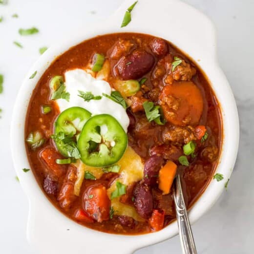 a bowl filled with chili topped with cheese and sour cream