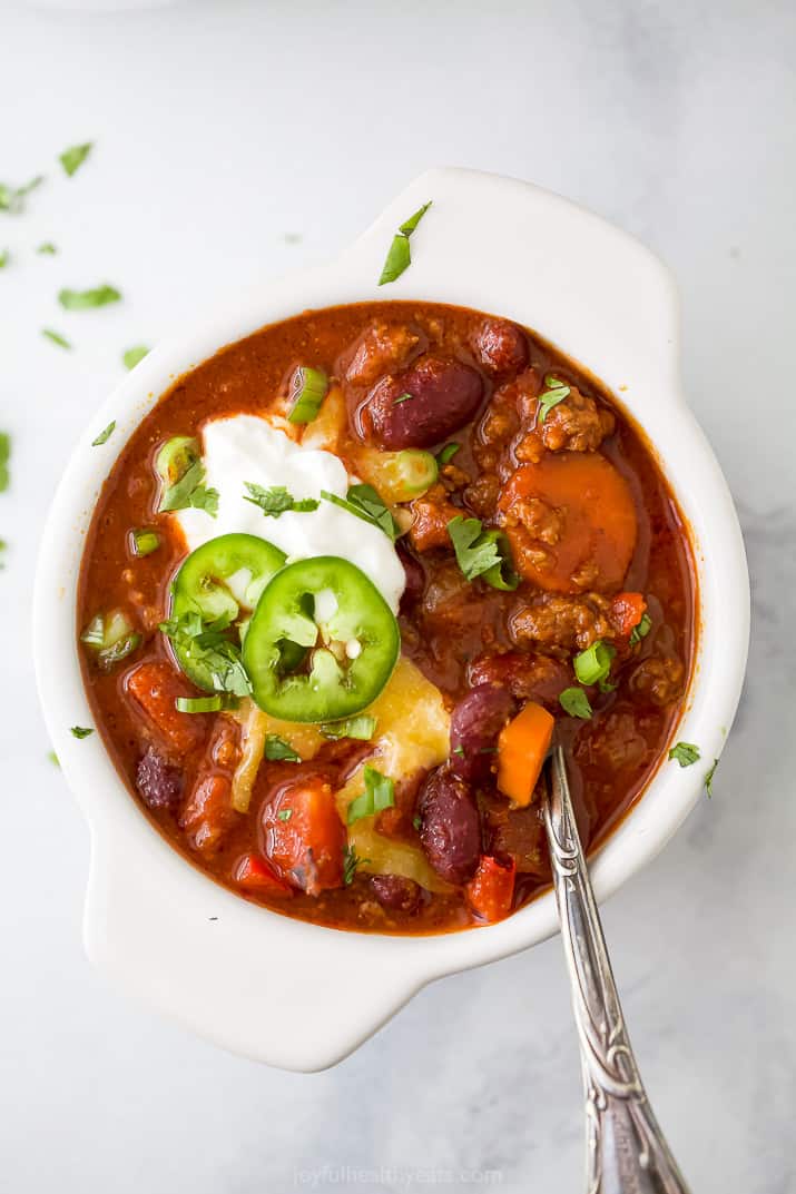 A bowl filled with chili and topped with cheese and sour cream.