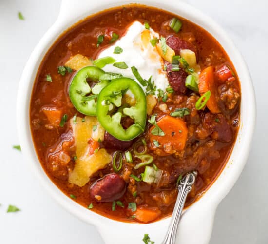 a crock bowl filled with beef chili and toppings