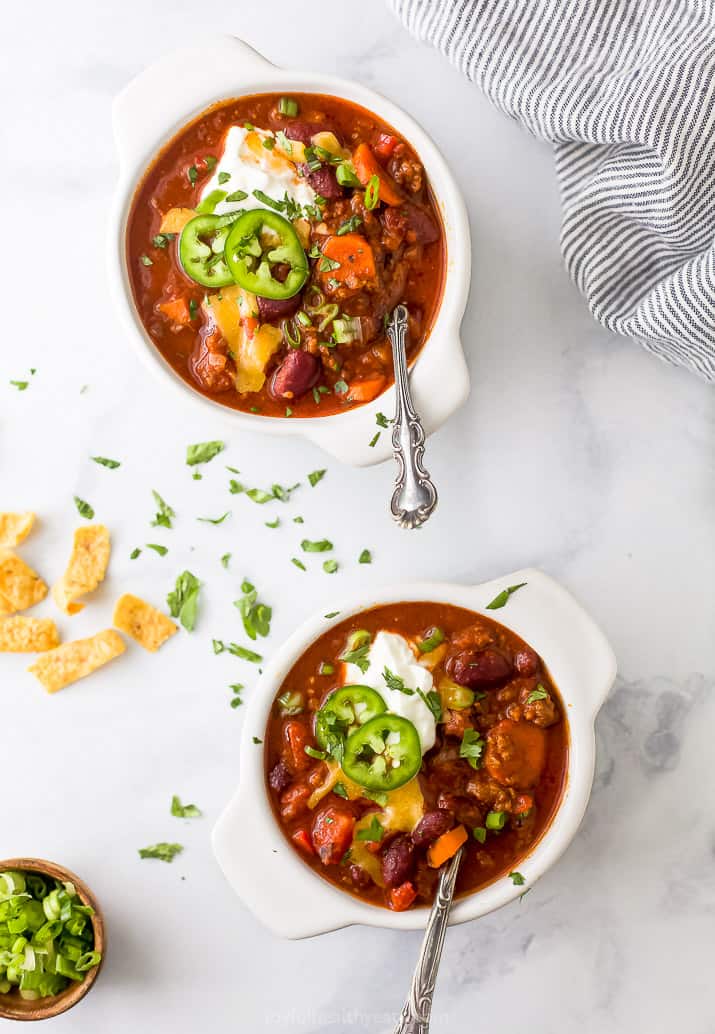 Two bowls with chili and topped with chili toppings.