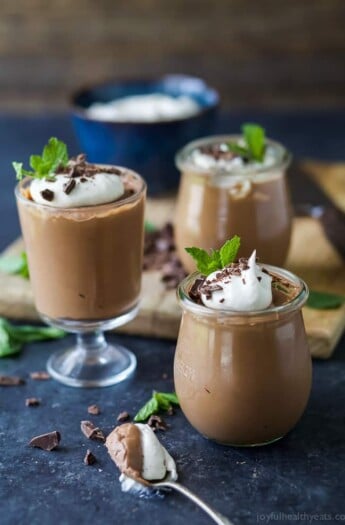 Three jars full of Easy Paleo & Vegan 3 Ingredient Peppermint Chocolate Mousse topped with chocolate shavings, whipped cream, and a mint garnish