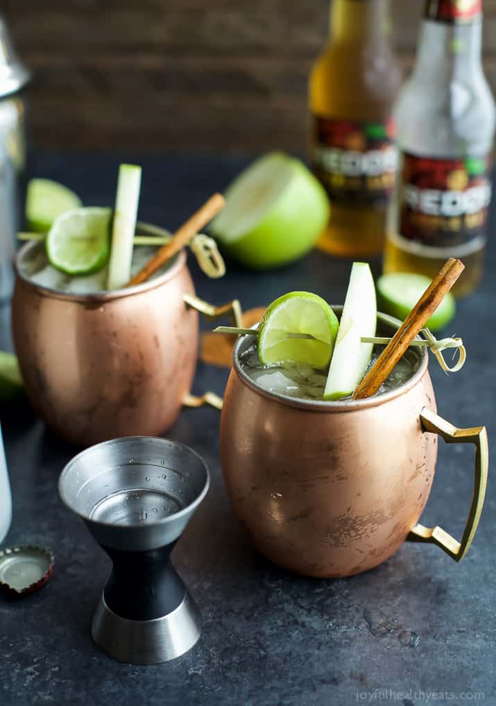 Apple cider Moscow mules in copper glasses near a jigger.
