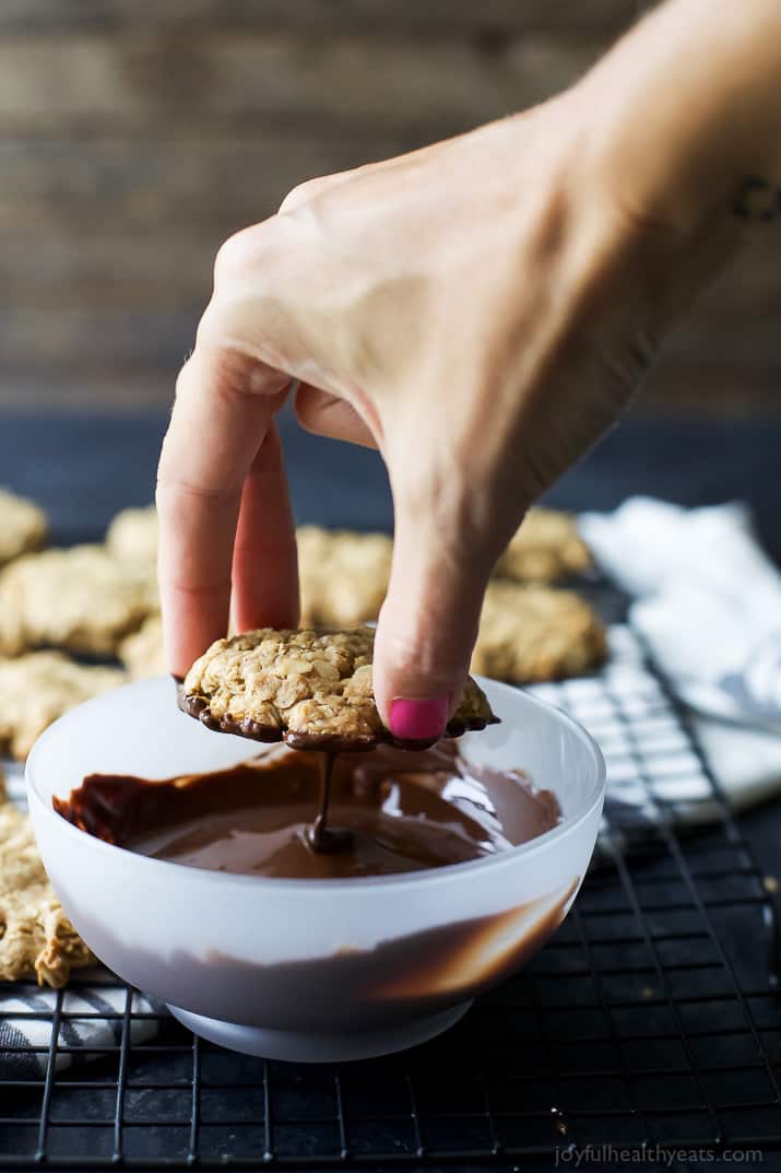 An Oatmeal Peanut Butter Cookie being dipped in a bowl of melted chocolate
