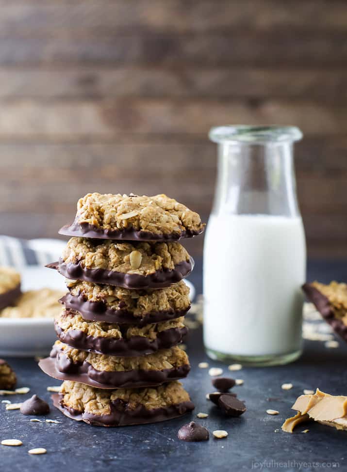 A stack of chocolate-dipped Oatmeal Peanut Butter Cookies next to a glass of milk