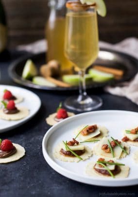 A Plate of Savory Appetizer Bites Beside a Glass of Champagne and a Plate of Sweet Bites