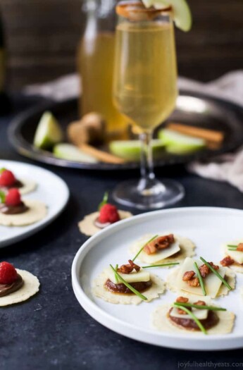 A Plate of Savory Appetizer Bites Beside a Glass of Champagne and a Plate of Sweet Bites