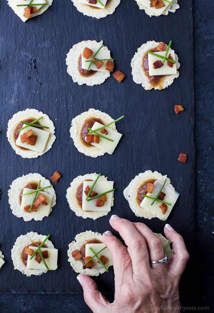 A Hand Grabbing a Savory Appetizer Bite From a Serving Board That's Full of Them