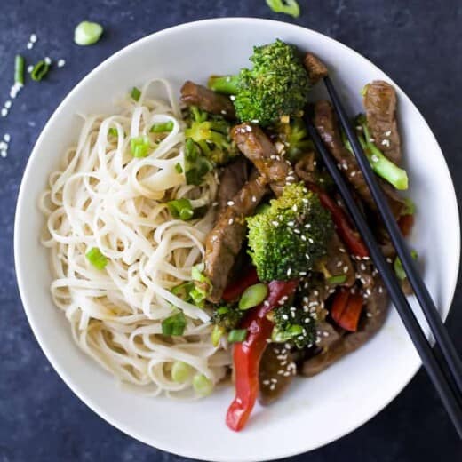 A shallow bowl on a kitchen countertop containing a stir fry with sliced green onions on top