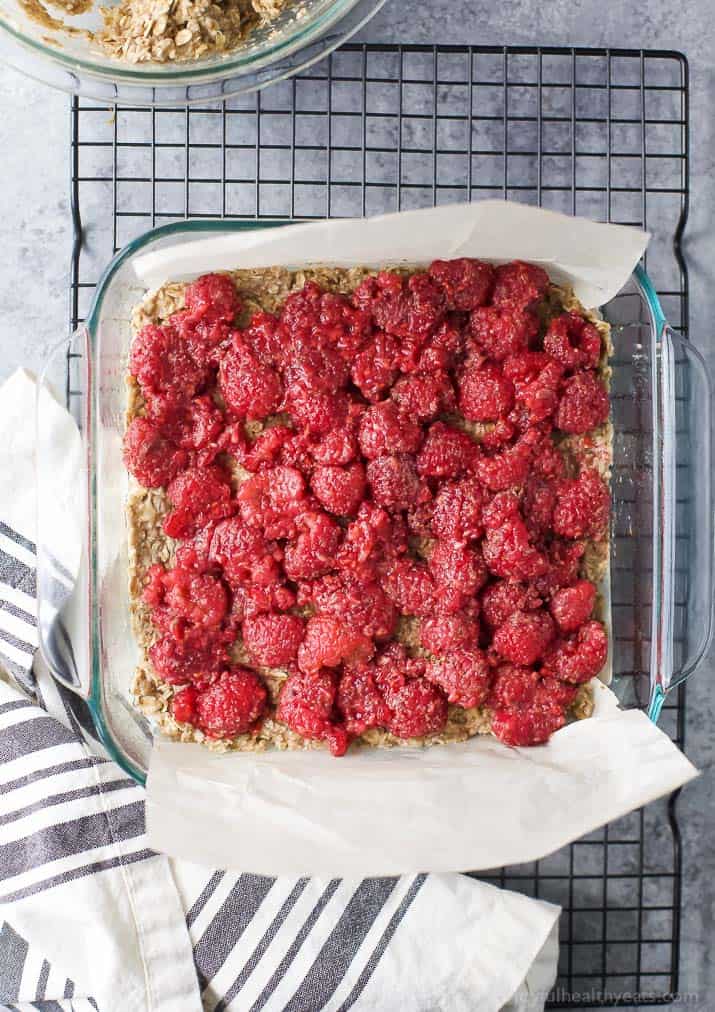 A Parchment-Lined Pan Containing Almond Raspberry Oat Bars with Some of the Parchment Overhanging