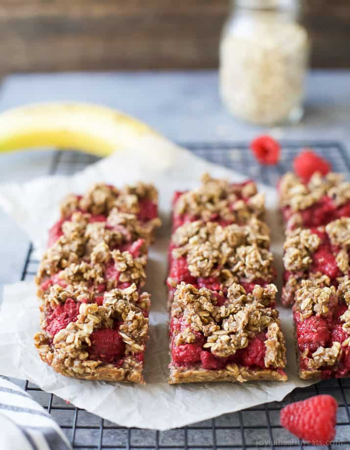 Raspberry Bars on a Cooling Rack with a Banana and a Jar of Oats in the Background