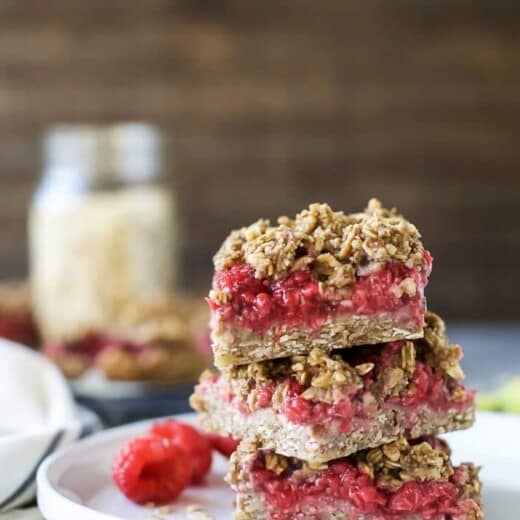 Three Raspberry Bars Stacked on a Plate with a Few Loose Berries