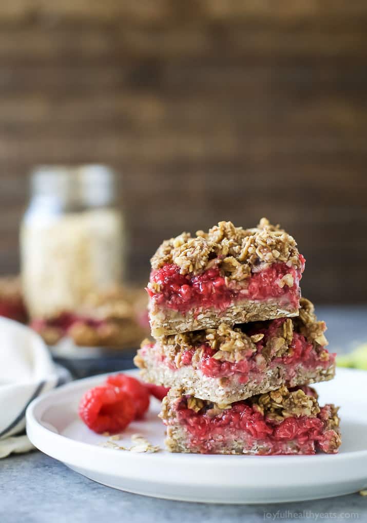 Three Raspberry Bars Stacked on a Plate with a Few Loose Berries