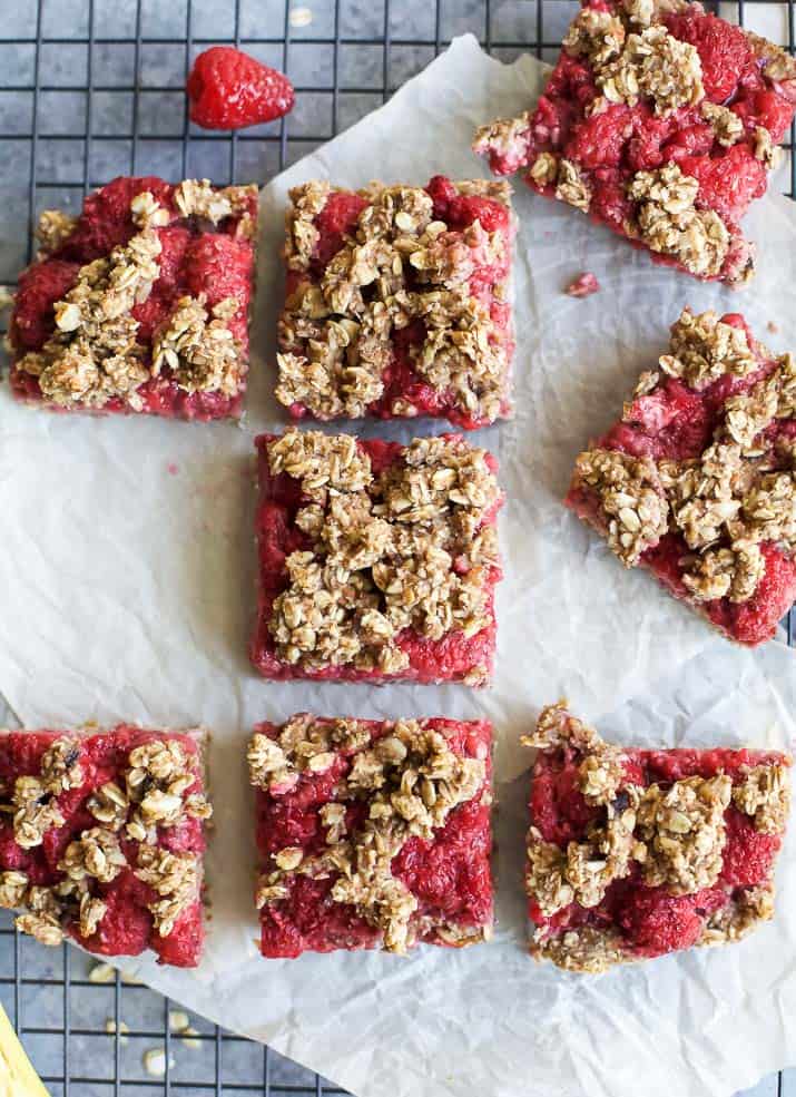 Eight Raspberry Oat Bars on a Cooling Rack Lined with Parchment Paper