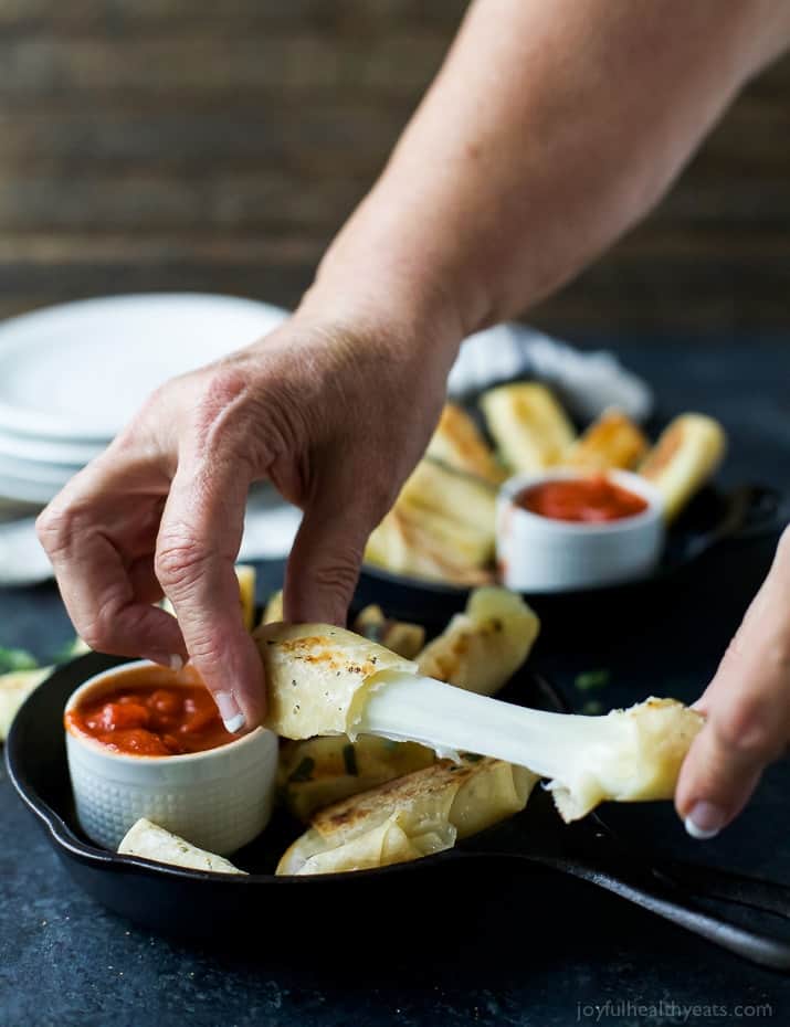 Skinny Baked Mozzarella Sticks wrapped in wonton wrappers with stretchy cheese