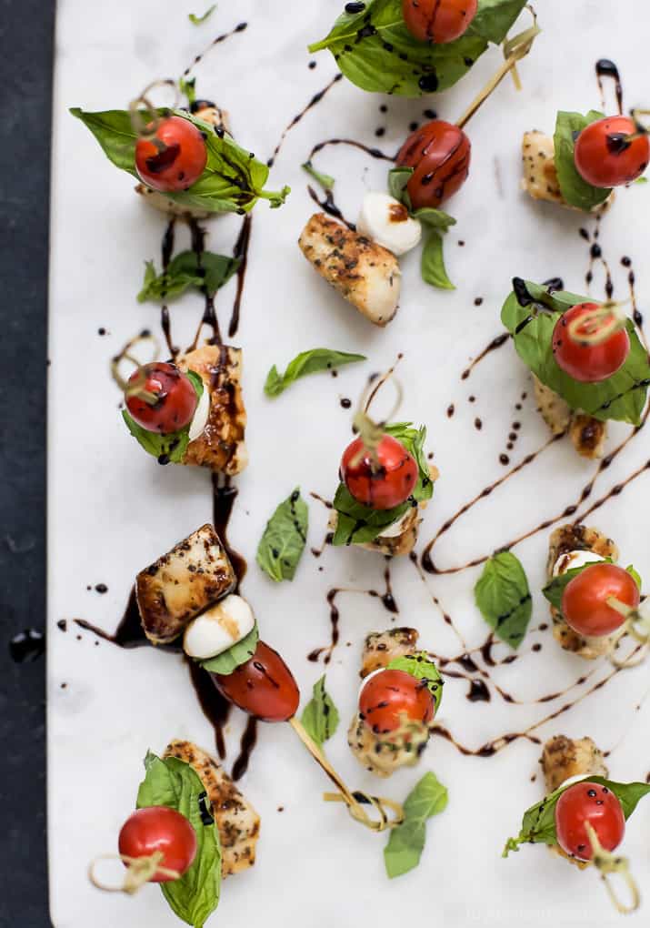 Top view of Caprese Chicken Skewers drizzled with a homemade Balsamic Glaze on a marble board