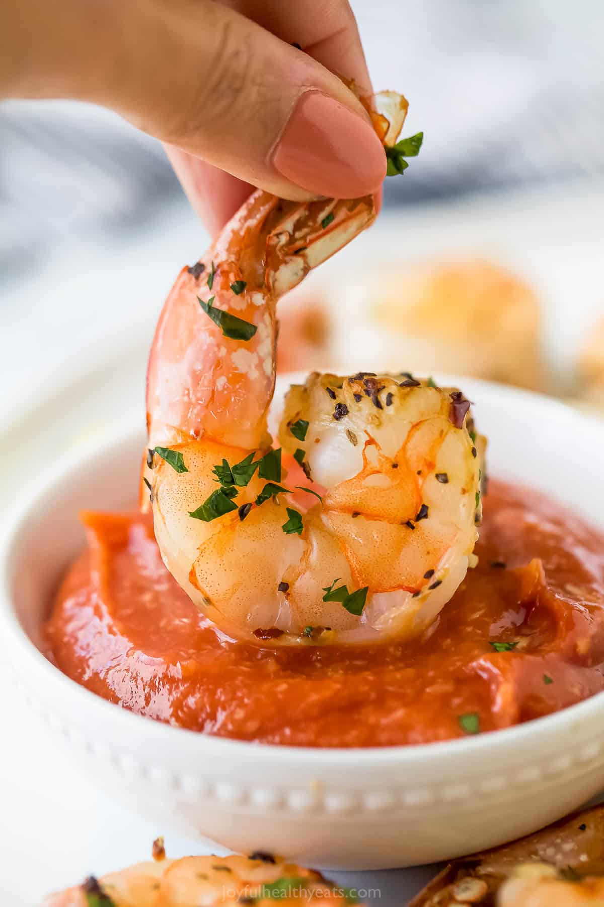 Dipping a roasted shrimp into the sauce. 