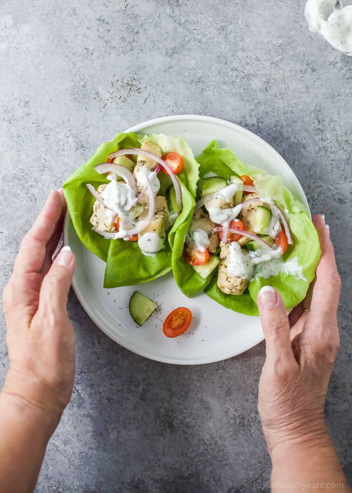 Top view of two Greek Chicken Lettuce Wraps with Tzatziki Sauce on a plate