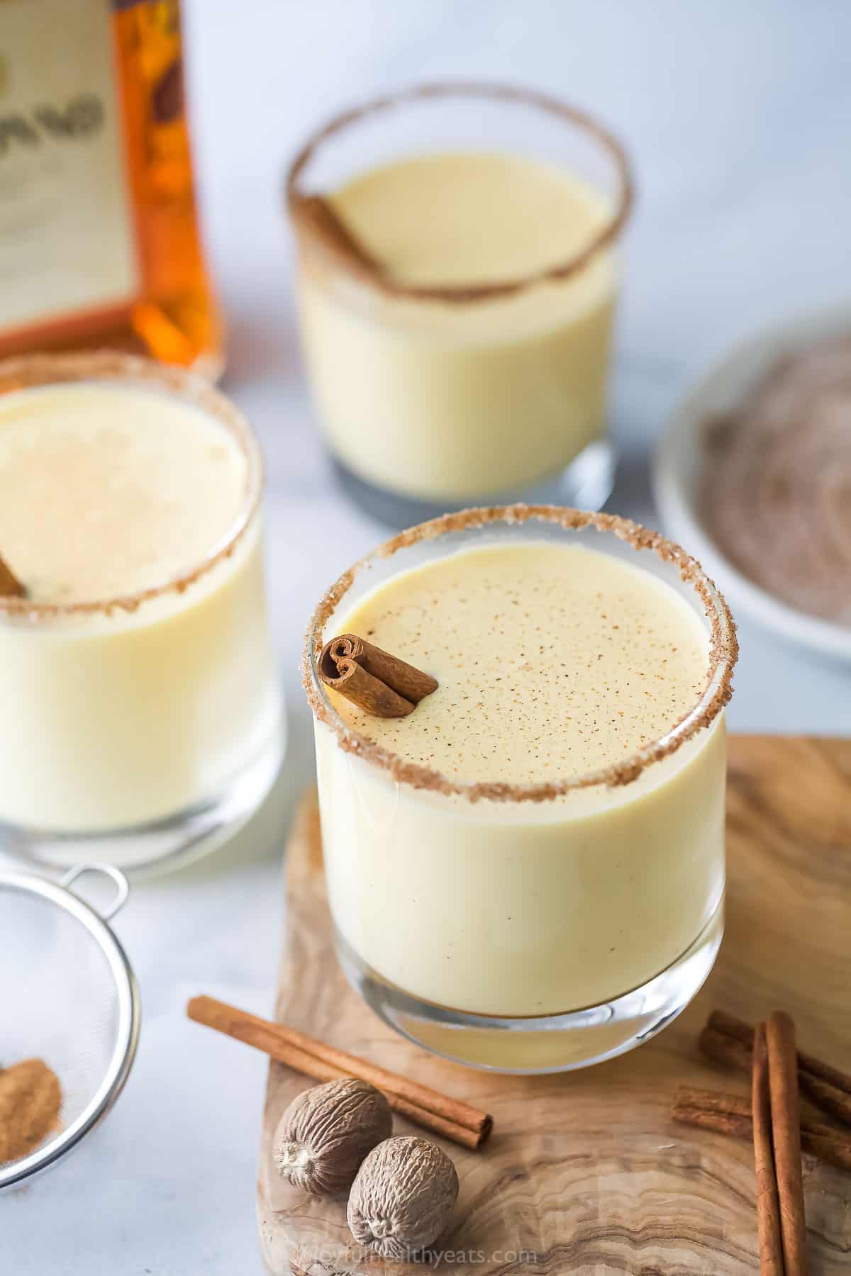 Three glasses of eggnog with a nutmeg cinnamon-sugar rim.