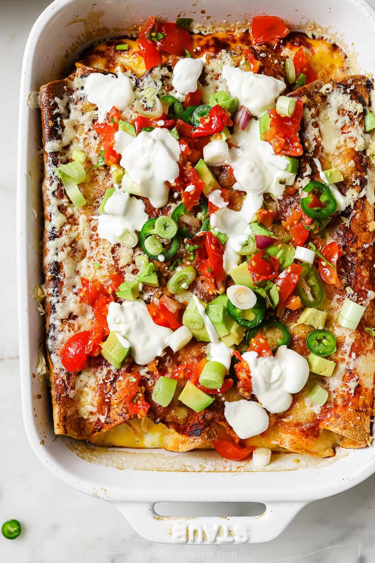 Breakfast enchiladas with sour cream, avocado, and sliced jalapeños.