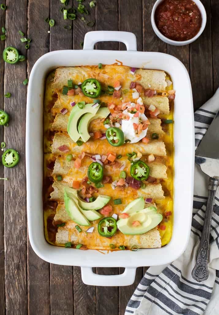 Easy Cheesy Overnight Breakfast Enchiladas filled with bacon, ham, veggies and an egg mixture. Make it the night before and bake in the morning! A delicious savory breakfast recipe perfect for brunch or the holidays!