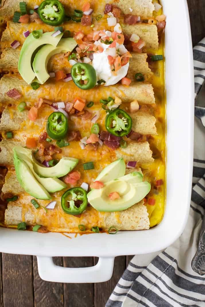Easy Cheesy Overnight Breakfast Enchiladas filled with bacon, ham, veggies and an egg mixture. Make it the night before and bake in the morning! A delicious savory breakfast recipe perfect for brunch or the holidays!