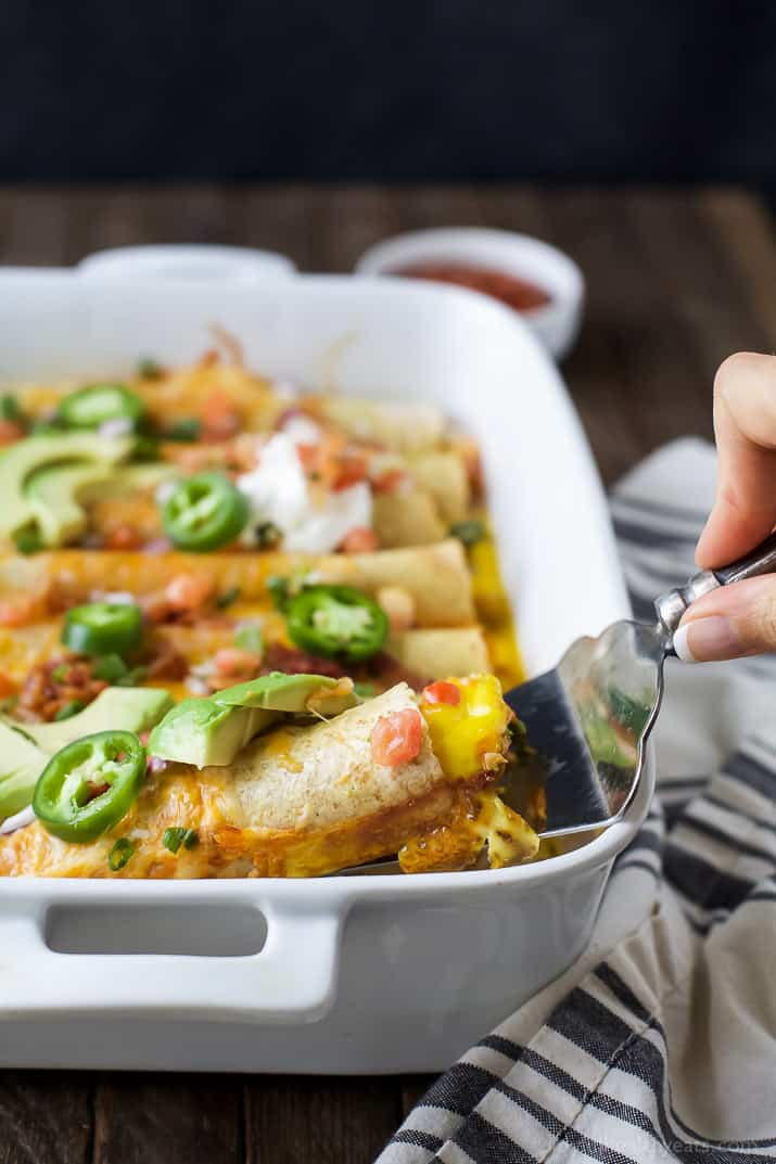 Easy Cheesy Overnight Breakfast Enchiladas filled with bacon, ham, veggies and an egg mixture. Make it the night before and bake in the morning! A delicious savory breakfast recipe perfect for brunch or the holidays!