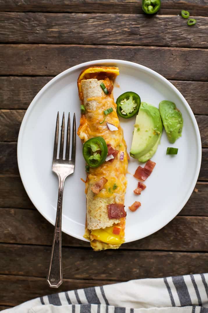 Easy Cheesy Overnight Breakfast Enchiladas filled with bacon, ham, veggies and an egg mixture. Make it the night before and bake in the morning! A delicious savory breakfast recipe perfect for brunch or the holidays!