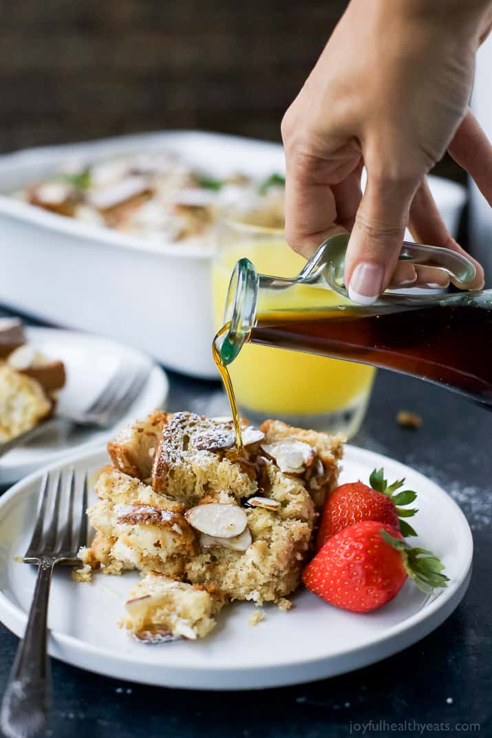 Maple syrup being poured over a serving of French toast casserole on a plate