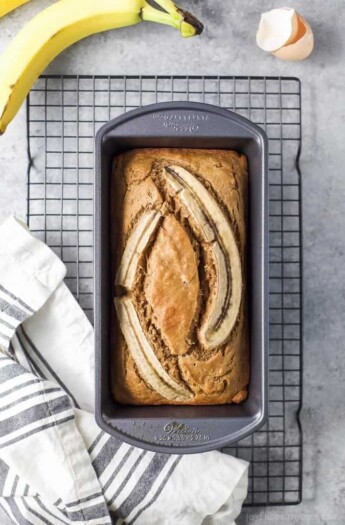 Banana bread in the loaf pan on a cooling rack.