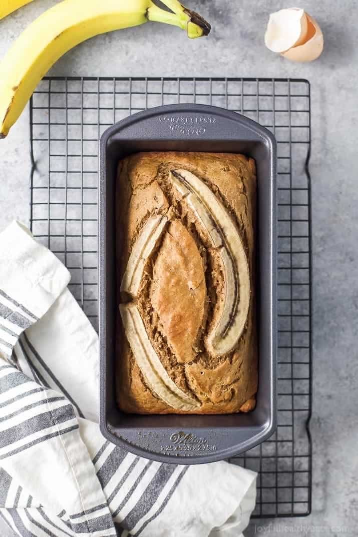 Banana bread in the loaf pan on a cooling rack.