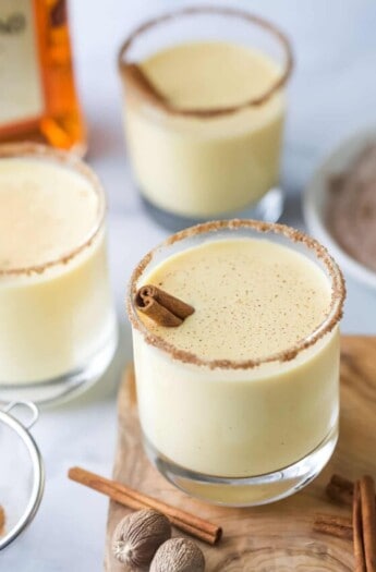 Three glasses of eggnog with a nutmeg cinnamon-sugar rim.