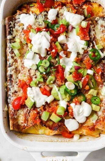 Breakfast enchiladas with sour cream, avocado, and sliced jalapeños.