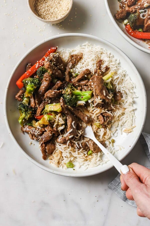 Plate of beef and broccoli stir fry with a side of fluffy rice noodles.