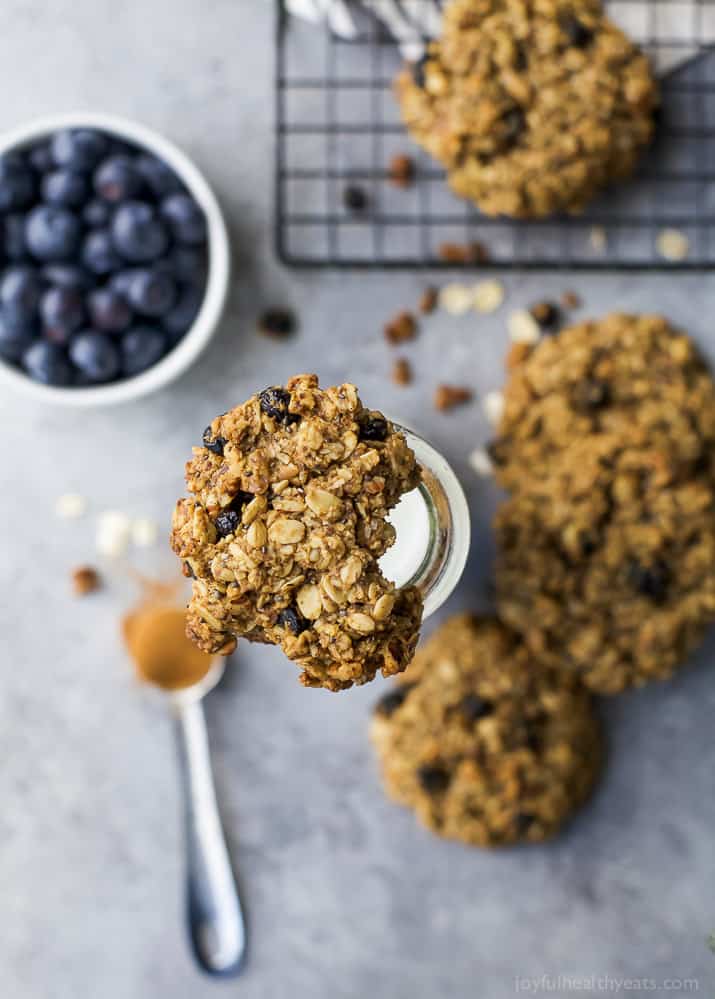 A bitten breakfast cookie balancing on top of a jar filled with milk