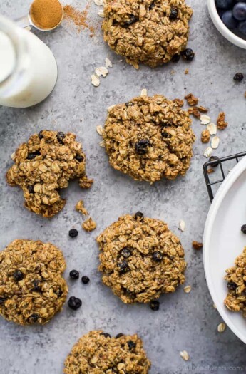 A bunch of breakfast cookies on a granite countertop beside a glass of milk