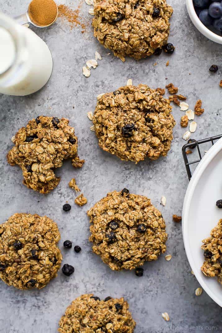 A bunch of breakfast cookies on a granite countertop beside a glass of milk