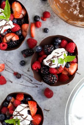 chocolate bowls made with a balloon filled with fresh berries & topped with coconut whipped cream