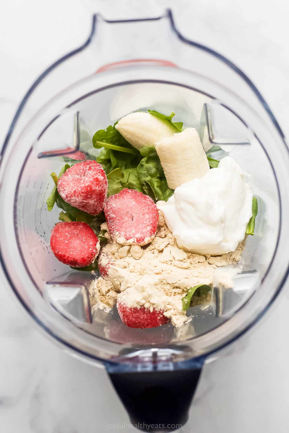 frozen fruit. protein powder, yogurt, and spinach in a blender