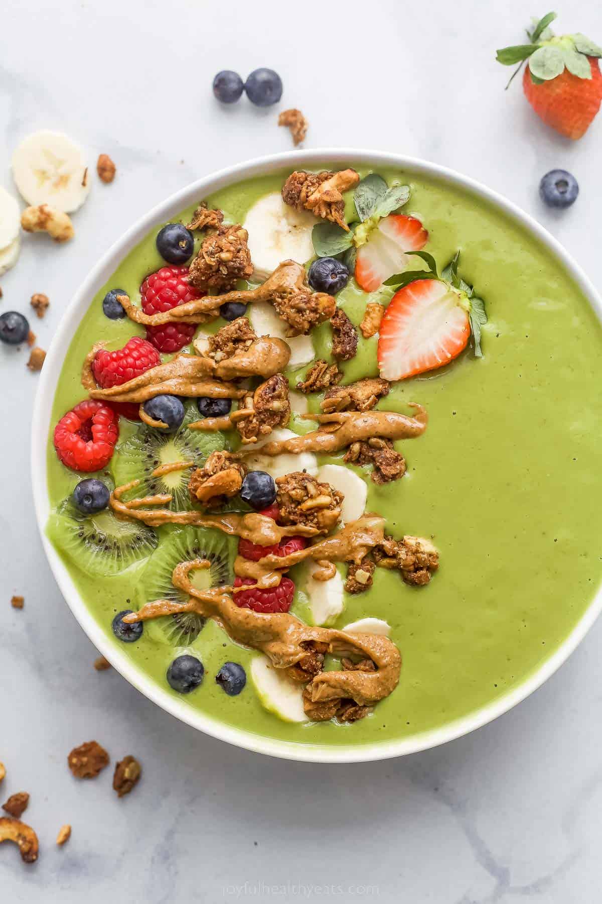 green smoothie bowl with fresh fruit and peanut ،er drizzle