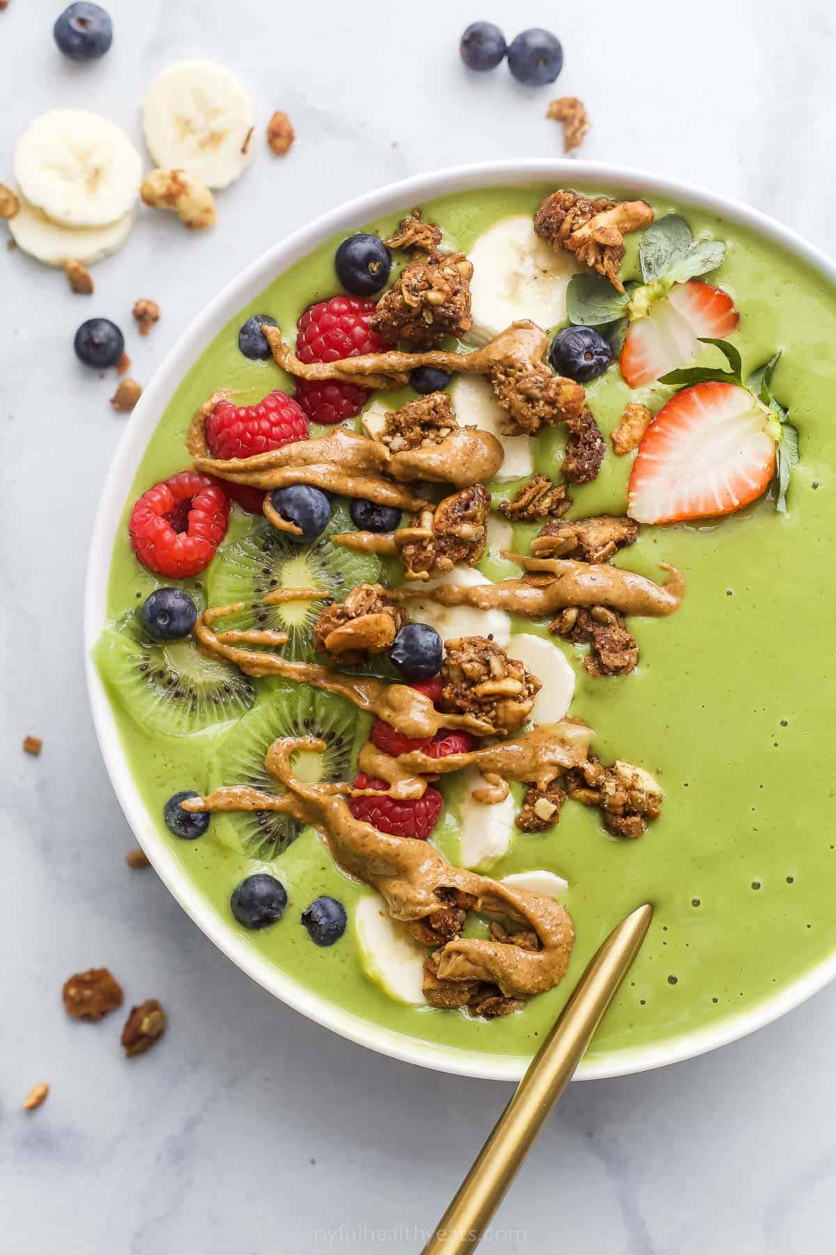 green smoothie bowl with fresh fruit and peanut ،er drizzle