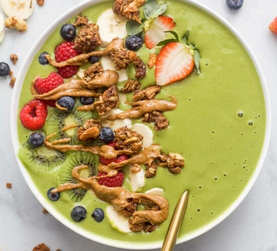 green smoothie bowl with fresh fruit and peanut butter drizzle