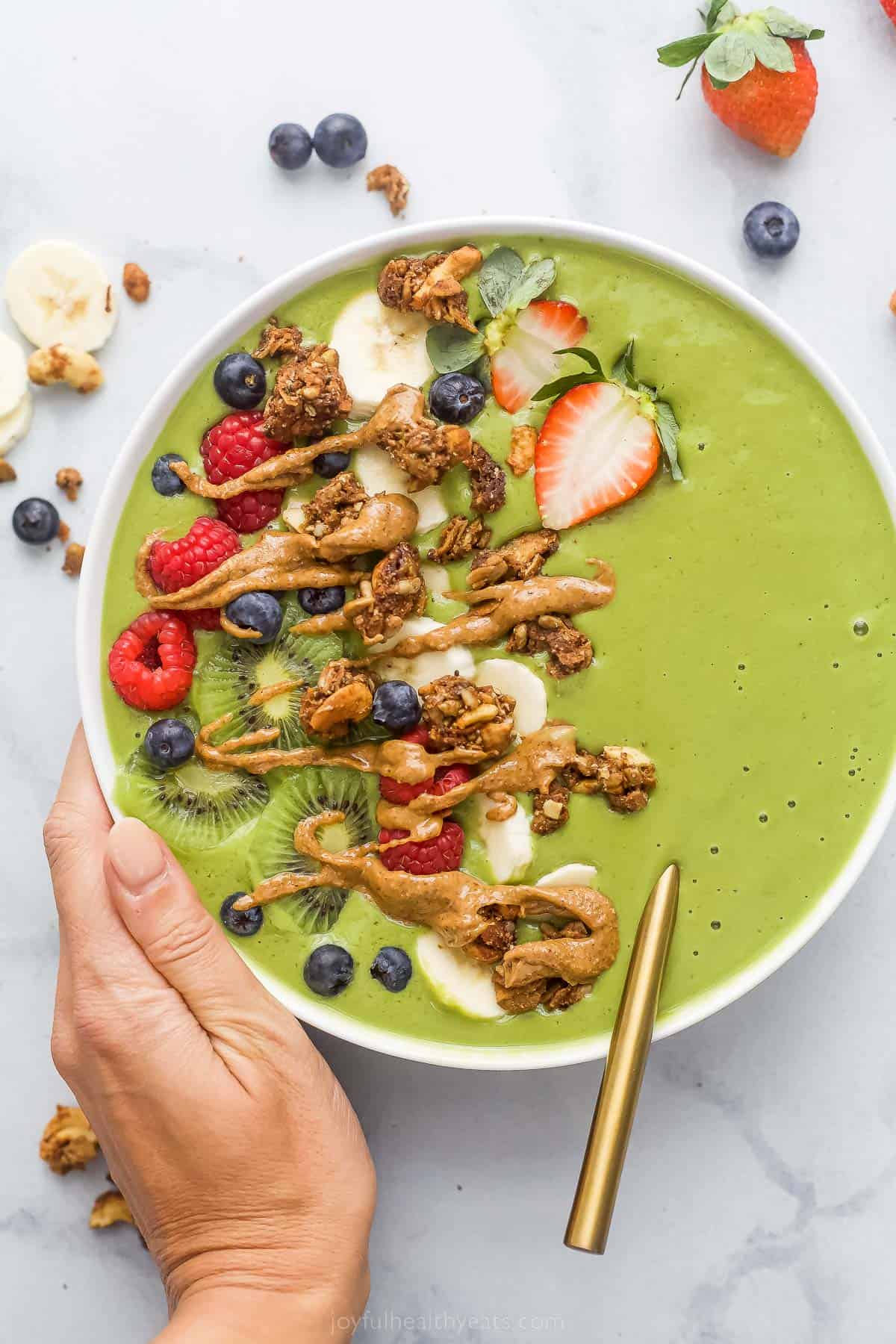 green smoothie bowl with fresh fruit and peanut ،er drizzle