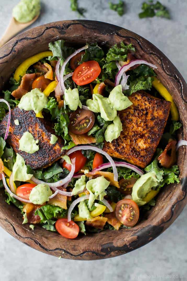 Top view of BLT Salmon Salad topped with creamy Avocado Dressing in a wooden bowl