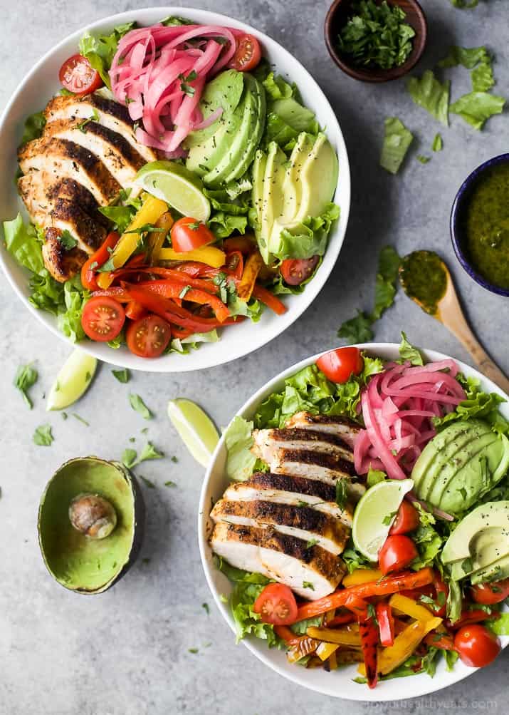 Top view of two bowls of Chicken Fajita Salad with fresh veggies, chipotle chicken, sliced avocado and zesty Chimichurri Dressing