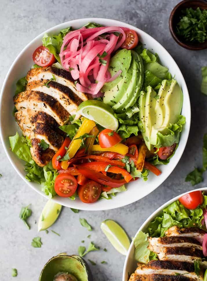 Top view of Chicken Fajita Salad in a bowl with fresh veggies, chipotle chicken, sliced avocado and zesty Chimichurri Dressing