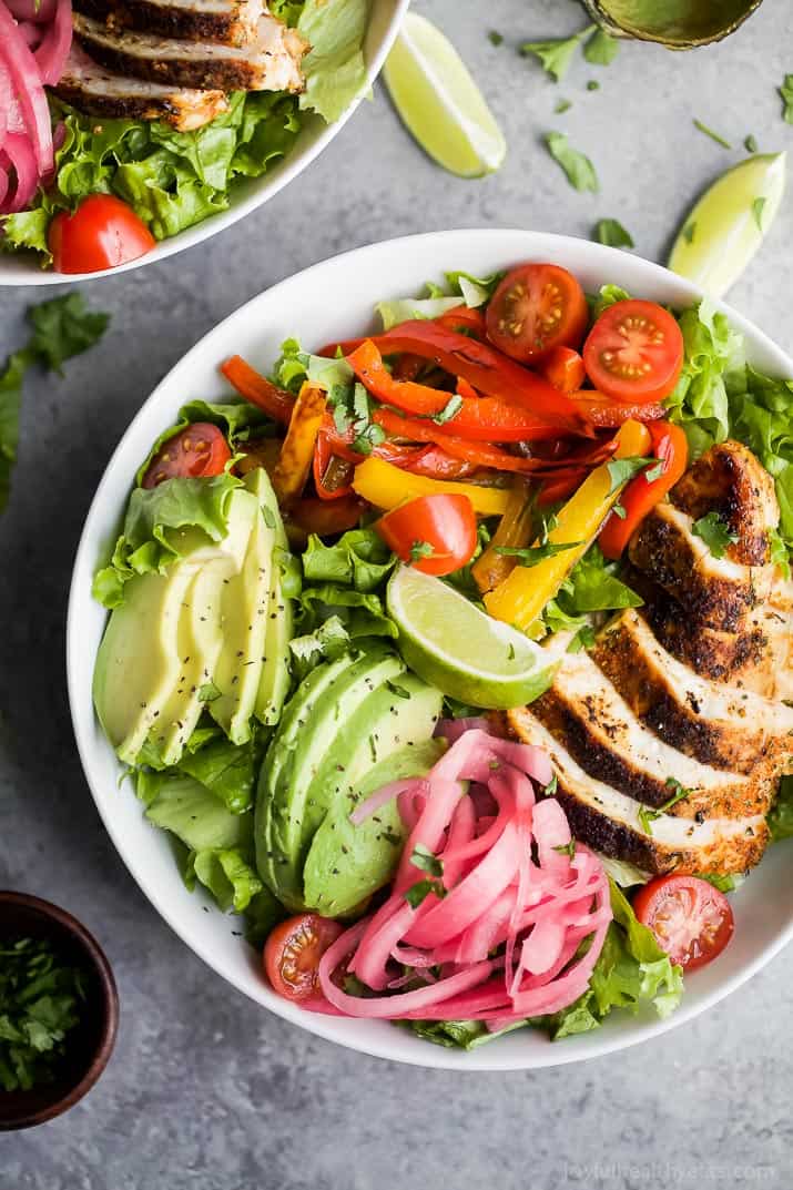 Top view of Chicken Fajita Salad in a bowl with fresh veggies, chipotle chicken, sliced avocado and zesty Chimichurri Dressing