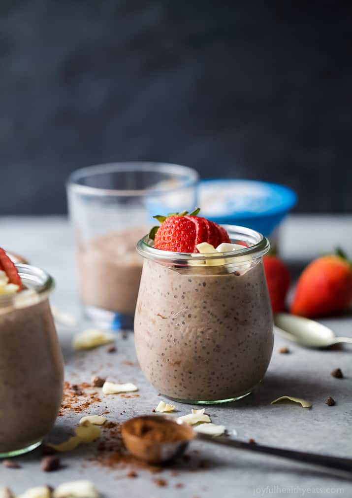 A glass of Coconut Dark Chocolate Chia Pudding topped with fresh strawberries and coconut