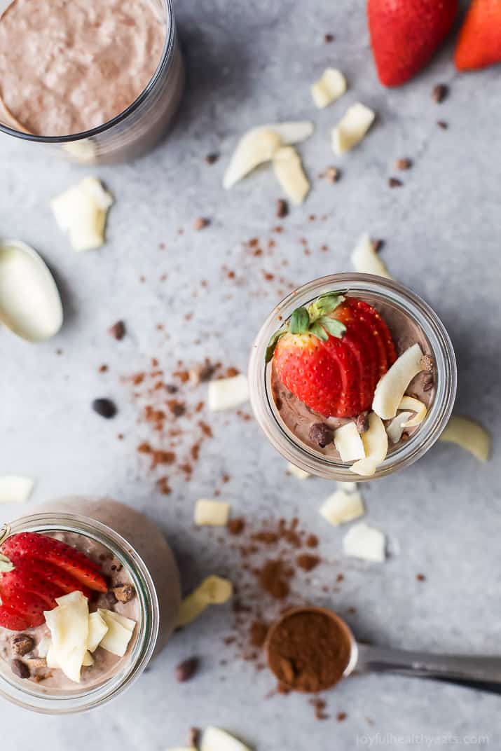 Top view of glasses of Coconut Dark Chocolate Chia Pudding topped with fresh strawberries and coconut